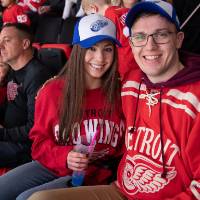 Two alumni smile for a photo while watching the game at the Detroit Red Wings GVSU Night